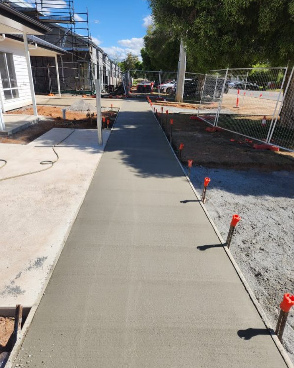 Poured concrete pathway at a scaffolded townhouse build site